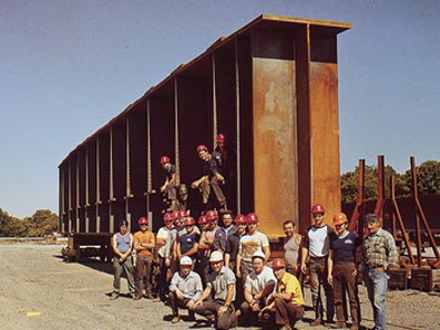 Williamsport Plant 3 co-workers stand in front of a large girder in 1985, the year the plant was acquired by High Steel Structures LLC.